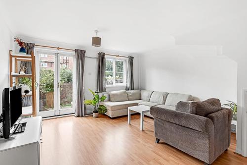 ein Wohnzimmer mit einem Sofa und einem TV in der Unterkunft Beautiful Three-Bedroom House in Richmond in Richmond upon Thames