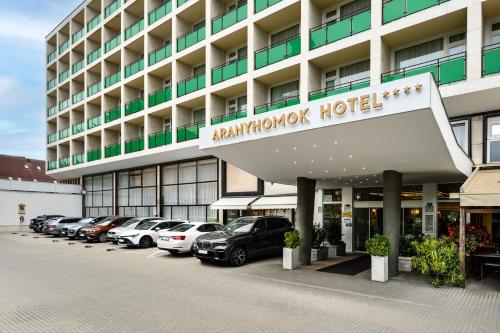 un hôtel avec des voitures garées dans un parking dans l'établissement Aranyhomok Business-City-Wellness Hotel, à Kecskemét