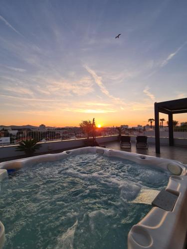 uma banheira de hidromassagem no telhado de um edifício com o pôr-do-sol em Zadar Sunset Penthouse with spectacular view and jacuzzi em Zadar