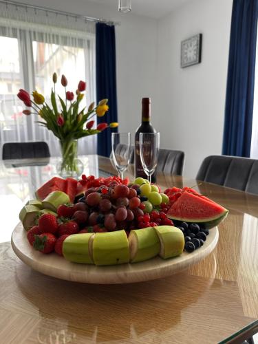 une assiette de fruits sur une table avec des verres à vin dans l'établissement Tatrzański Domek & SPA, à Poronin