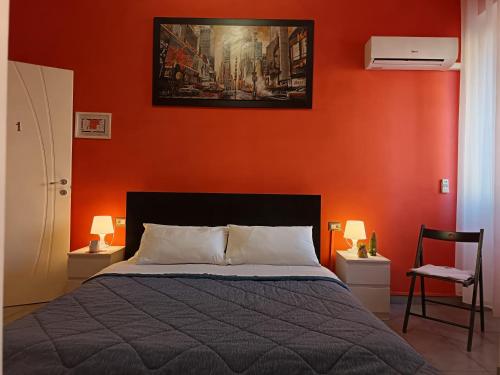 a bedroom with an orange wall with a bed at Adriatic Room 50 m dalla stazione Ferroviaria di Ciampino e dalla navetta aeroportuale in Ciampino