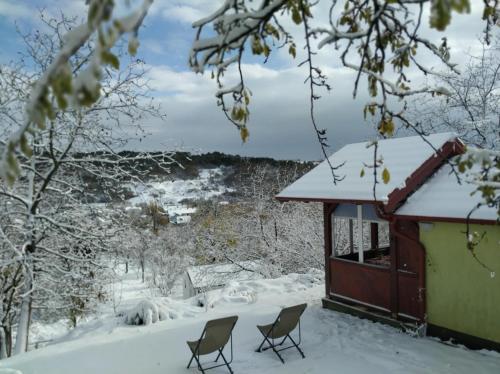 une maison avec deux chaises dans la neige dans l'établissement Holiday home Nanin konak 2, à Vrdnik