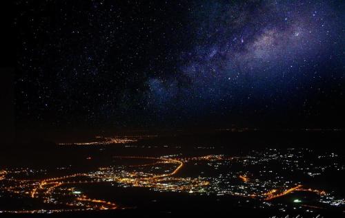 een uitzicht op een stad in de nacht met een sterrenhemel bij The View in Al Ḩamrāʼ