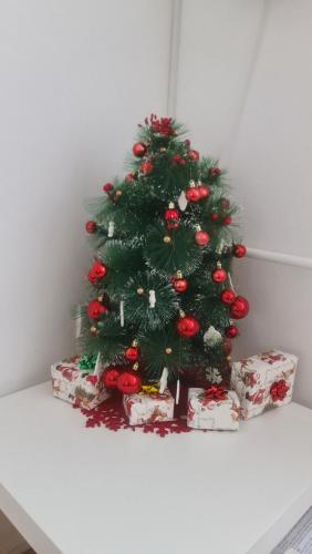 ein Weihnachtsbaum auf einem Tisch mit Geschenken in der Unterkunft Apartman Zlatovo Stan Na Dan in Požarevac