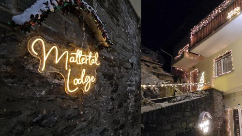 una señal en el lateral de un edificio con luces en Mattertal Lodge, en Embd