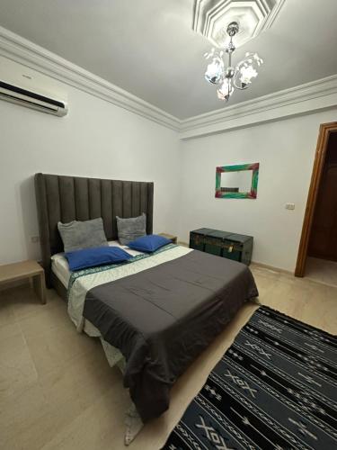 1 dormitorio con 1 cama grande con almohadas azules en Coquette appart de plage, en Hammam Sousse