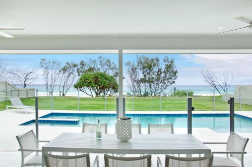 una sala da pranzo con tavolo e piscina di Sentosa on Tugun - Beachfront 5 Bedroom a Gold Coast