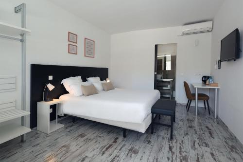 a white bedroom with a white bed and a desk at Le Néliö in Aix-en-Provence