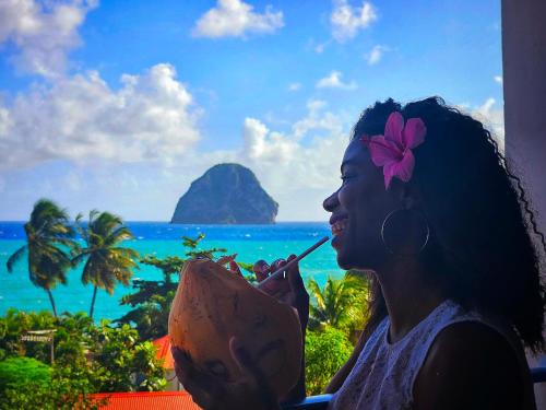 una mujer comiendo una bebida con vistas al océano en Studio A101, près de la mer Village du Diamant, en Le Diamant