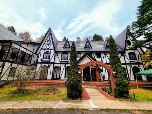 uma grande casa branca e preta com um arco em ペンションアルマ em Katashina