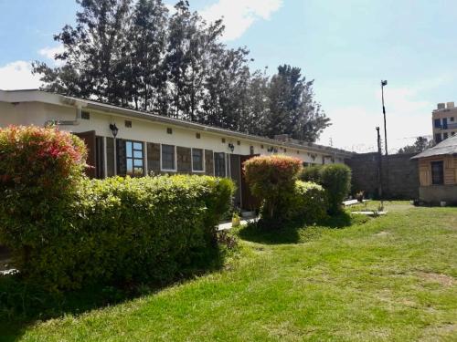 a building with bushes in front of a yard at Simply stylish Gardens Naivasha in Naivasha