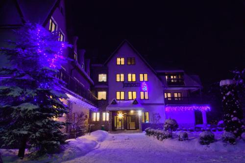 a lit up house with purple lights in the snow at DW Janosik in Muszyna