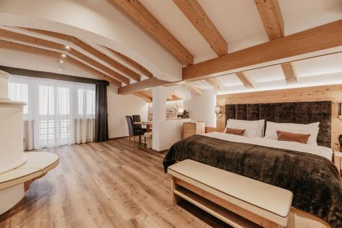 ein großes Schlafzimmer mit einem großen Bett und Holzdecken in der Unterkunft Freina Mountain Lifestyle Hotel in Wolkenstein in Gröden