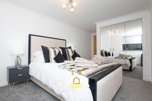 a white bedroom with a large bed and a mirror at Panacotta House - SJA Stays - Modern 1 Bed Apartment in Aberdeen