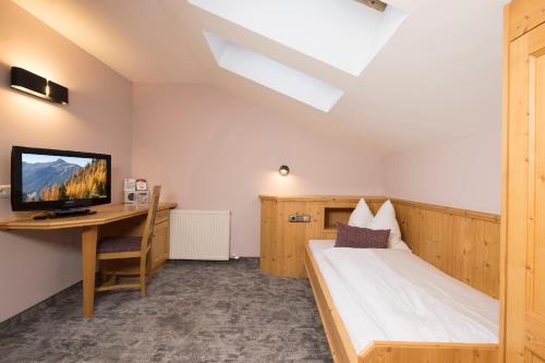 1 dormitorio con 1 cama y escritorio con TV en Gasthaus Jakober, en Alpbach