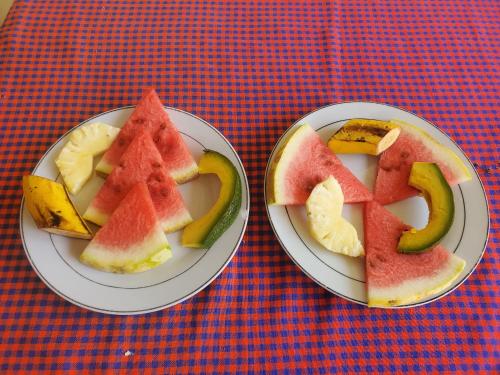 dos platos con rodajas de fruta en una mesa en L&J Modern Backpackers Kinondoni, en Dar es Salaam