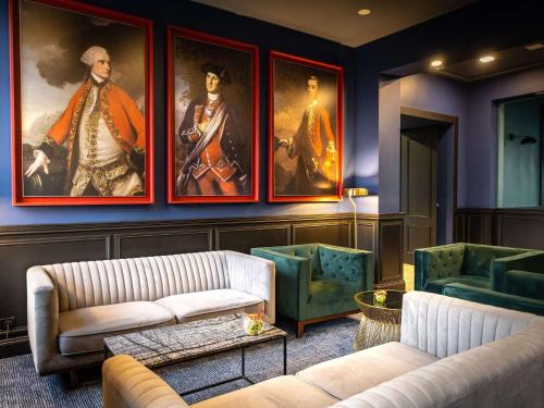 uma sala de estar com dois sofás e pinturas na parede em Hôtel Mercure Rochefort La Corderie Royale em Rochefort