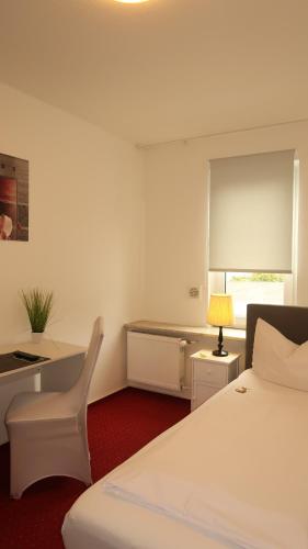 a bedroom with a white bed and a desk and a window at Hotel Zur Kripp in Koblenz