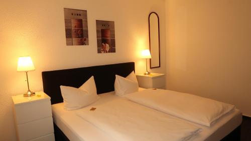 a bedroom with a white bed with two lamps at Hotel Zur Kripp in Koblenz