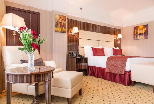 una habitación de hotel con una cama y un jarrón de flores en Golden Tulip Addis Ababa, en Addis Ababa