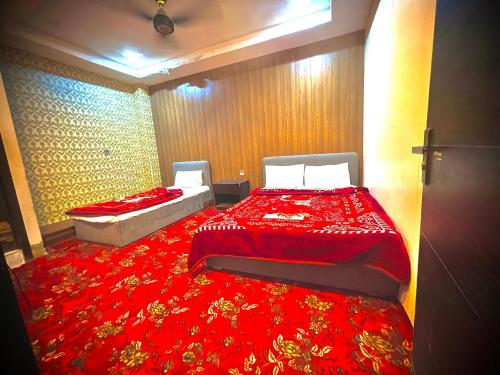 um quarto com 2 camas e um cobertor vermelho em Al Aqsa Guest House em Islamabad