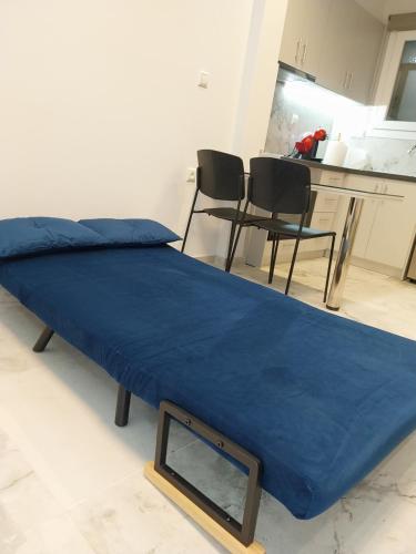 uma cama com um lençol azul e duas cadeiras em Elario studio em Larisa