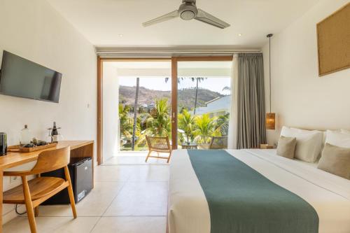 Schlafzimmer mit einem Bett, einem Schreibtisch und einem Fenster in der Unterkunft Sikara Lombok Hotel in Kuta Lombok