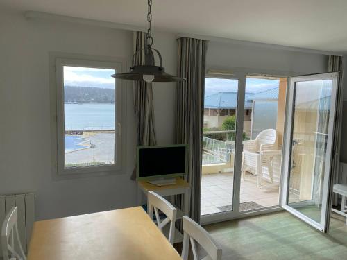 een eetkamer met een tafel en een televisie en een balkon bij Cap Morgat in Crozon