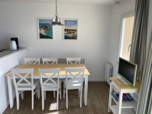 een eetkamer met een tafel en stoelen en een televisie bij Cap Morgat in Crozon