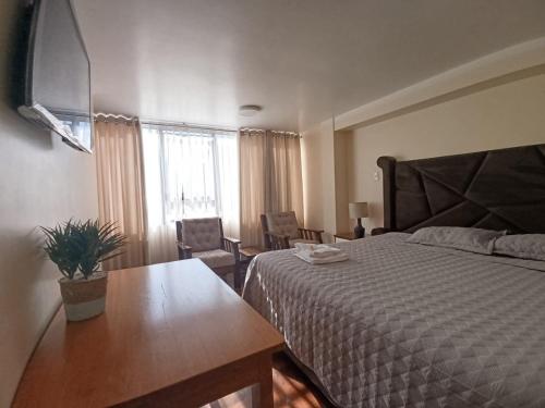 a bedroom with a bed and a table and a window at casa SKALA in Puno