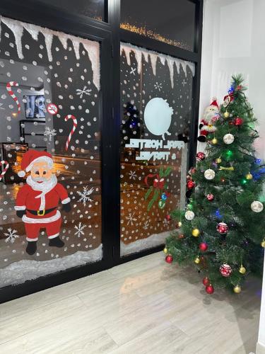 Uma porta de Natal com uma janela do Pai Natal e uma árvore de Natal. em Aral Hostel em Berati