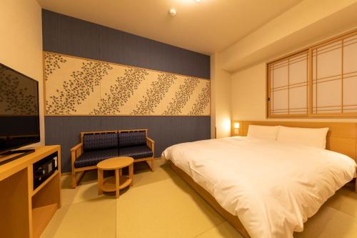 a bedroom with a bed and a television and a chair at Onyado Nono Asakusa Natural Hot Spring in Tokyo