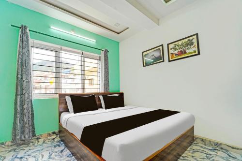 1 dormitorio con 1 cama grande y pared verde en Super Hotel O Vijaynagar Road formerly Anmol Peace Stay, en Ooty