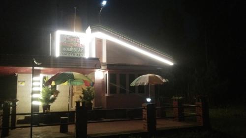 two umbrellas in front of a restaurant at night at Rock peak view homestay in Avathi