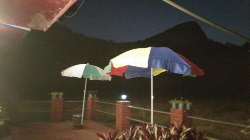 two colorful umbrellas on a patio at night at Rock peak view homestay in Avathi