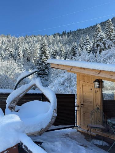 una casa cubierta de nieve junto a una cabaña en Hotel Borjomi Verde, en Borjomi