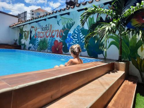 un jeune enfant assis dans une piscine avec une fresque murale dans l'établissement Travelero Hostel & Tours, à Santa Cruz de la Sierra