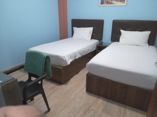 Cette chambre comprend 2 lits et une chaise. dans l'établissement CARDOS HOSTAL, à Pisco