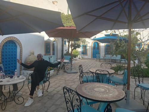 un uomo sta ballando in un patio con tavoli e sedie di Hôtel Bou Fares a Sidi Bou Saïd