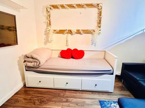 Una cama en una habitación con dos almohadas rojas. en Stay in London - CENTRAL LONDON 30 minutes - WIMBLEDON 14 mins, en Londres