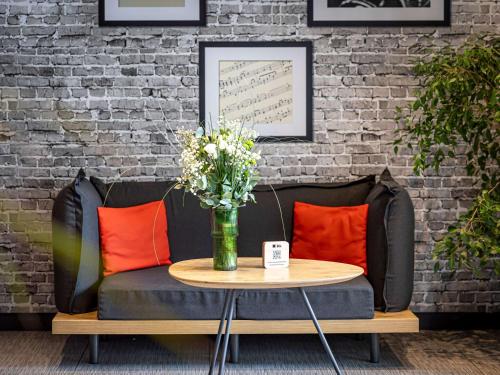 eine Couch mit einer Vase Blumen auf dem Tisch in der Unterkunft ibis Daumesnil Porte Doree in Paris