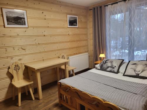 a bedroom with a bed and a desk and a window at Pokoje Pod Lasem in Kościelisko