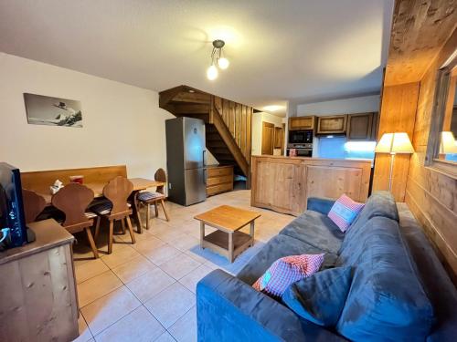 ein Wohnzimmer mit einem blauen Sofa und einer Küche in der Unterkunft Appartement triplex avec piscine, parking, animaux acceptés - FR-1-624-169 in Samoëns