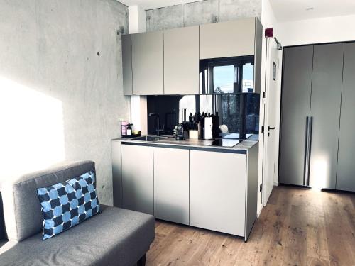 Mikes Apartments Munich في ميونخ: مطبخ مع دواليب بيضاء واريكة في الغرفة