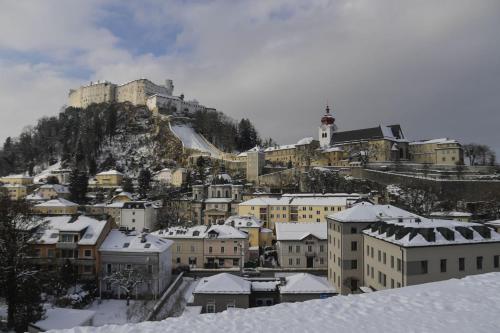 een besneeuwde stad met een kasteel op een berg bij JUFA Hotel Salzburg in Salzburg