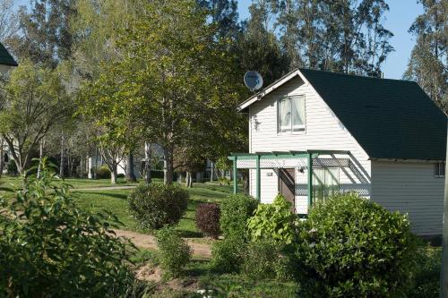 una pequeña casa blanca con techo negro en Cabañas Huallilemu Norte - Caja Los Andes, en El Quisco