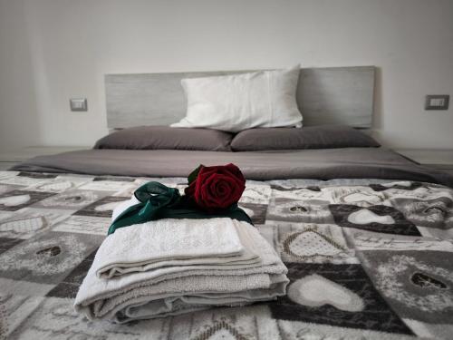 un letto con asciugamani e una rosa rossa sopra di La dimora sul lido ad Alghero