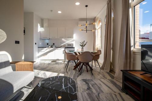 een woonkamer met een tafel en stoelen en een keuken bij William Martin Apartments in Huelva