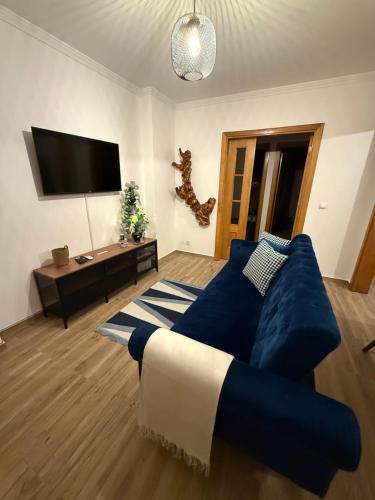 a living room with a blue couch and a tv at Cas'A Ferreirinha - Your Home In Douro in Peso da Régua