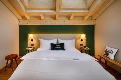 a bedroom with a large white bed with a green wall at Hotel Sport Klosters in Klosters